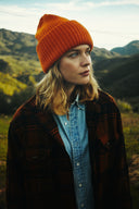Woman wearing the Wyeth Parker Wool Beanie in Orange with a plaid jacket