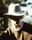 Man in sunglasses and a brown sweater wearing the Matty wool felt cowboy hat in Grey.